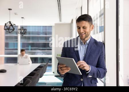 Smiling professional managing financial results on tablet in conference room Stock Photo