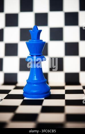 Blue king chess piece standing on a black and white chessboard, a bold concept of strategy, power, leadership and decision making Stock Photo
