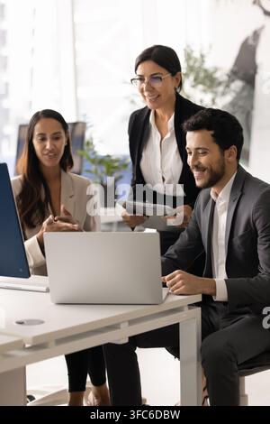 Smiling multiethnic professional business team collaborate around laptop Stock Photo