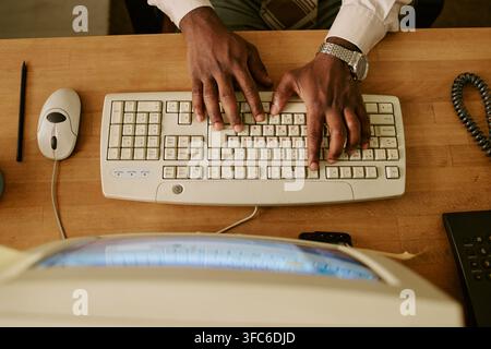 Overhead View of Black Man Typing on Vintage Keyboard in Retro Office Stock Photo