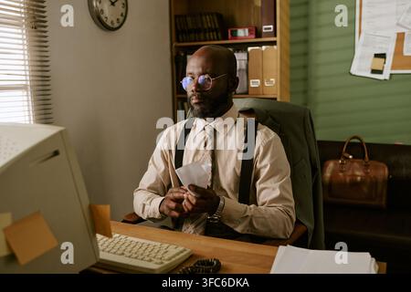Black Middle Aged Businessman Working on Retro Computer in Office Stock Photo