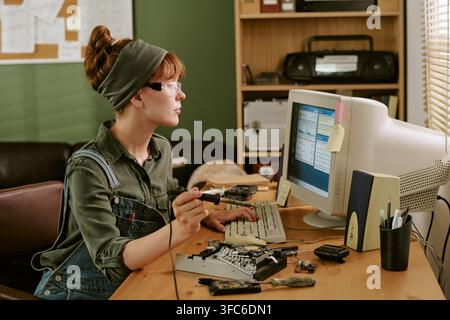 Woman Repairing Computer Hardware in Retro Office Setting Stock Photo