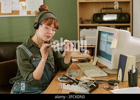 Woman Engineer Repairing Vintage Computer Circuit Board in Retro Office Stock Photo