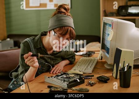 Woman Soldering Electronic Components in Retro Office Workspace Stock Photo