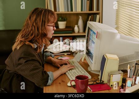 Woman Working on Retro Computer in Vintage Office Setting Stock Photo
