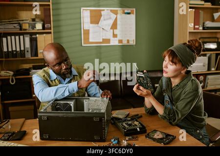 Diverse Colleagues Repairing Vintage Computer in Retro Office Stock Photo