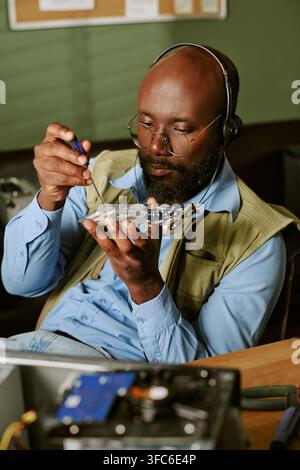 Black Man Repairing Computer Circuit Board in Retro Office Stock Photo