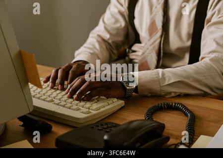 Black Man Typing on Retro Computer Keyboard in Vintage Office Stock Photo