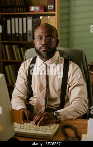 Portrait of Black Man Working on Retro Computer in Office Stock Photo