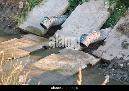 Industrial drainage system with heavy plastic sewage pipes discharging dirty wastewater from concrete structures Stock Photo