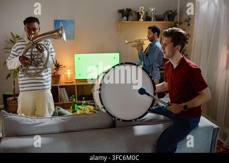 Diverse Men Playing Musical Instruments While Watching Football Game Stock Photo