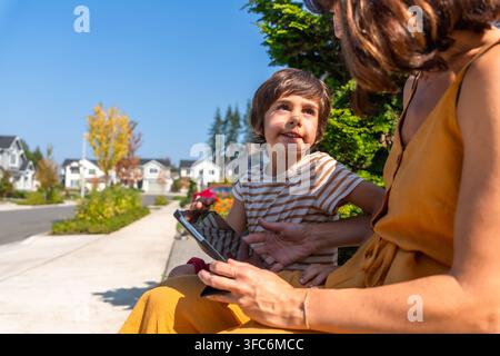 Mother and son using digital tablet in suburban neighborhood Stock Photo