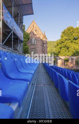 Illuminated blue rows of seats in front of a historic church in the open-air theatre, Calwer Klostersommer Festival, Hirsau Abbey, Calw, Germany Stock Photo