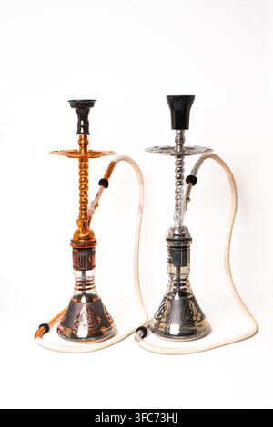 A pair of Khalil Maamoon branded hookahs with ornate metal stems glass bases and hoses is displayed on white. Stock Photo