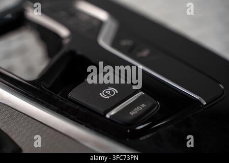 Close up of an electronic parking brake switch and automatic hold button in a modern vehicle center console. Stock Photo