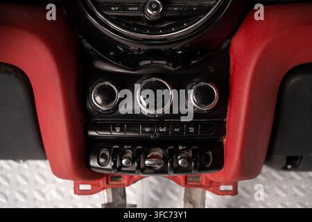 Close up of an installed automotive climate control panel with rotary dials and toggle switches in a red dashboard. Stock Photo