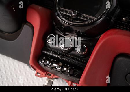 Close up of an installed automotive climate control panel with rotary dials and toggle switches in a red dashboard. Stock Photo