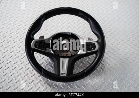 A black multifunction automotive steering wheel with control buttons is isolated on a white studio background. Stock Photo