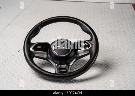 A Jaguar multifunction steering wheel with the manufacturer emblem is photographed as a dismantled automotive interior component. Stock Photo