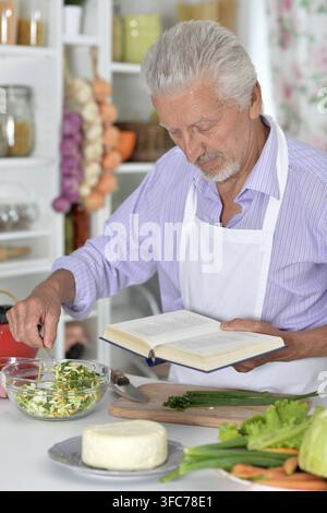 Elderly man in apron preparing healthy food at home Stock Photo