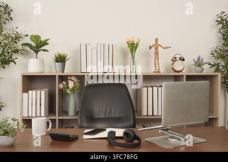 A modern home office setup with a desk with chair, bookshelves, and decorative plants that create a professional yet cozy workplace Stock Photo