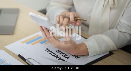 A businesswoman focuses on analyzing financial data using a tablet and is preparing for an annual financial report in a modern office Stock Photo