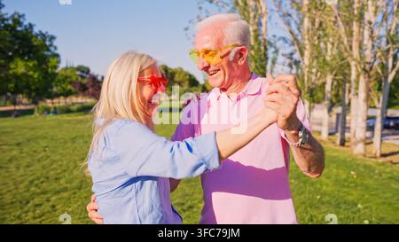 Happy senior couple enjoying dancing outdoors in a park Stock Photo