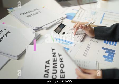 A professional accountant analyses financial reports using a calculator, focusing on data and cost management Stock Photo
