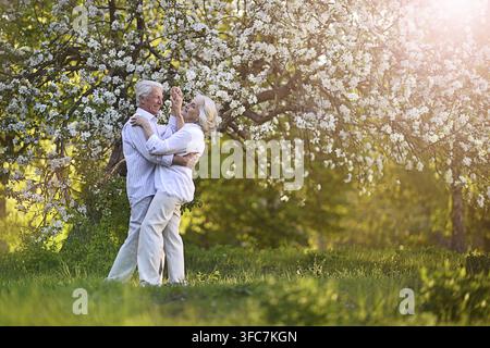 Beautiful elderly couple dancing in apple orchard Stock Photo