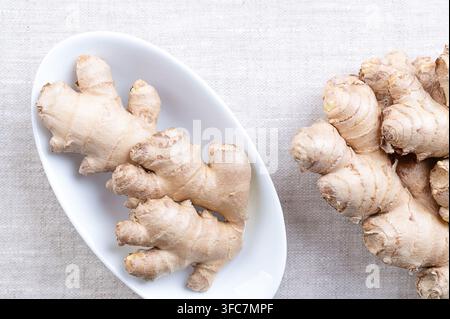 Fresh ginger root, in oval white bowl on linen. Rhizomes of Zingiber officinale, used in cooking for its flavor, and in traditional folk medicine. Stock Photo