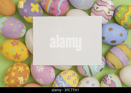 A blank card between glowing Easter eggs on a green background, ideal for festive greetings and messages Stock Photo