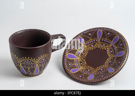Decorative ceramic painted cup and saucer on white background, close up. Decorative porcelain cup and saucer painted with acrylic paints, handwork, do Stock Photo