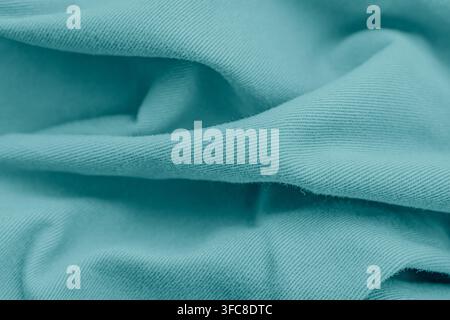 Close up top view of draped turquoise cotton twill fabric with soft shadows and wave folds background horizontal stock photo. Stock Photo