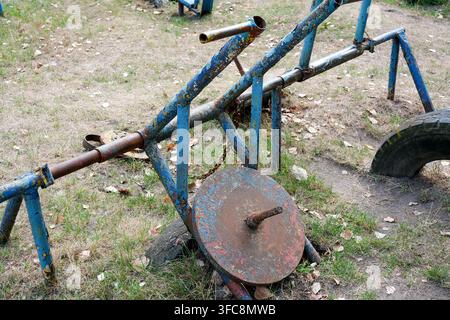 Brutal homemade gym training machine with flaking paint and big rusty iron weight plate. Close up view of rugged blue weathered metal pipe structures Stock Photo