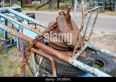 Brutal homemade training equipment with old car tire, thick steel chain, and heavy rusty brake discs used as counterweights. Close up detail of rugged Stock Photo