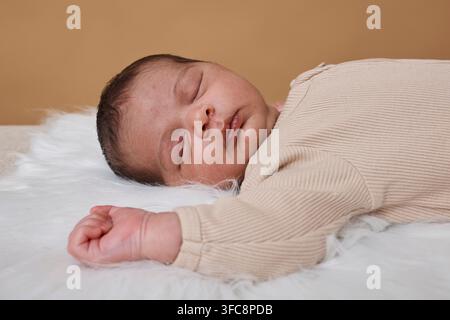 Sleeping Newborn Baby Lying on Soft Fur Blanket in Neutral Ribbed Onesie, Cozy Newborn Portrait Stock Photo
