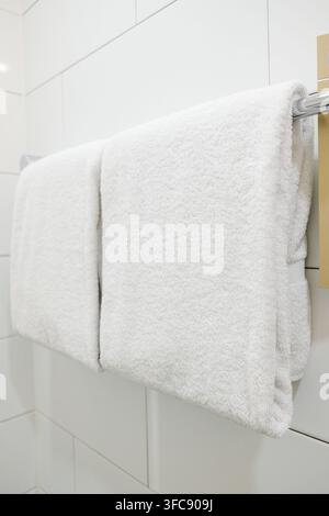 Clean white bath towels hanging on a chrome towel rail Stock Photo