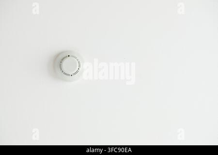 White smoke detector and fire alarm sensor on a ceiling Stock Photo