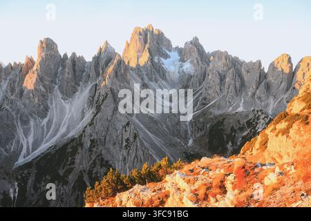 Sunlit cliffs frame the dramatic peaks of Cadini di Misurina in the Dolomites. Rugged mountain landscape with fresh snow and sharp limestone formations Stock Photo