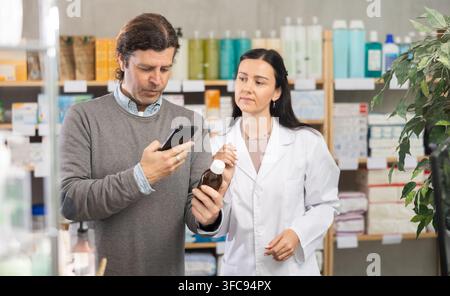 Man buyer scans syrup qr code with woman pharmacist Stock Photo