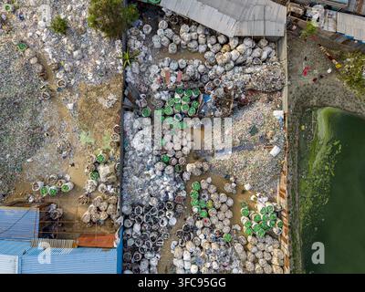 Aerial view of a plastic waste recycling facility in Bakalia with bags of sorted plastic bottles stored in an industrial yard near a pond in Chattogra Stock Photo