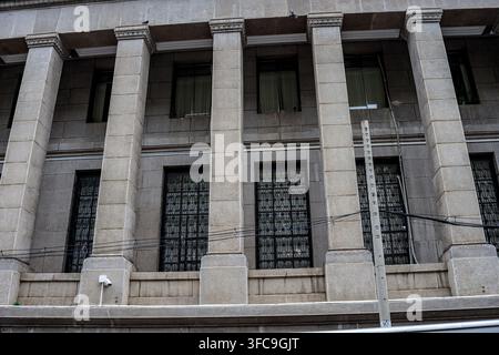 Ho Chi Minh, vietnam - July 28 2024: A low-angle view of a grey stone building featuring large square columns with decorative capitals and windows pro Stock Photo
