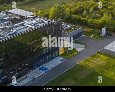 Aerial view of the Selvita building featuring a modern glass facade with hexagonal patterns, rooftop mechanical equipment, and surrounding green space Stock Photo