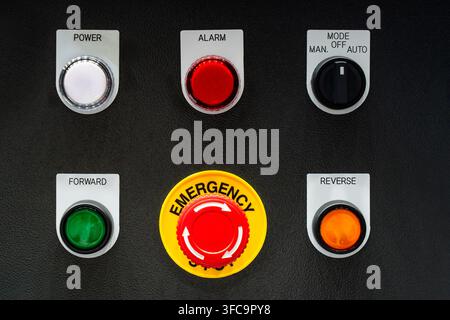 Industrial control panel with red emergency stop button, power indicator, mode switch, forward and reverse push buttons Stock Photo