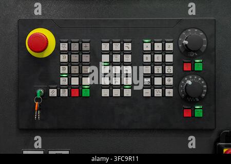 Industrial CNC operator control panel featuring emergency stop, X Y Z axis controls, spindle start buttons, rotary adjustment knobs and machine operat Stock Photo