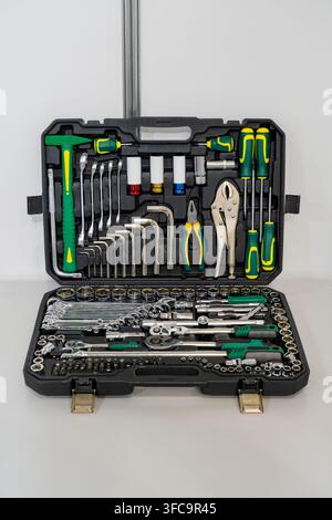 Open professional tool box kit with green and yellow handles containing sockets, wrenches, hammer, and hand tools Stock Photo