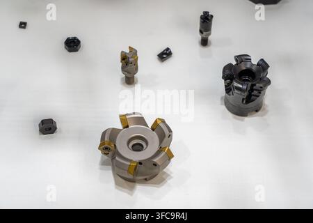 Assortment of CNC face milling cutters with indexable carbide inserts and end mills displayed on white surface Stock Photo
