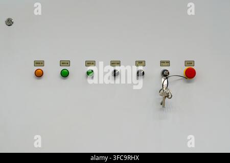 Industrial electrical control panel with push buttons, key switch lock, rotary switches, and red emergency stop button Stock Photo