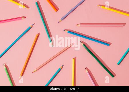 Creative colorful pattern made of colored pencils on pastel pink background. Minimal school and creative education concept. Flat lay style. Top view. Stock Photo