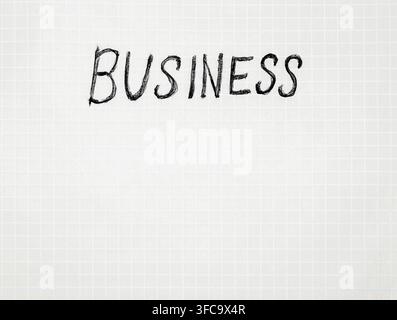 Handwritten word 'BUSINESS' in bold, black chalk on light gray grid paper. Clean, minimalist aesthetic Stock Photo